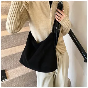 Detail of black suede hobo tote bag featuring adjustable shoulder strap with metal eyelets