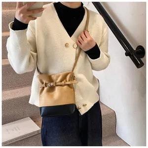 Détail du sac seau en daim mat avec bordure en cuir et boucle décorative