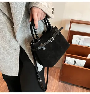 Detail of a black mini bucket bag with leather handles and silver metal hardware