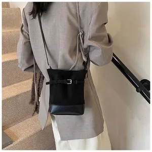 Détail du sac seau en daim noir avec coutures en cuir et boucle argentée décorative
