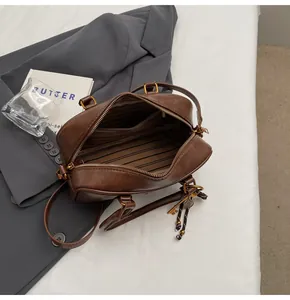Internal view of dark brown Boston bag with striped lining and zipper pocket detail