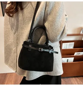Close-up of black frosted suede tote bag with decorative metal buckle and adjustable strap
