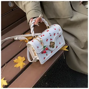 Detailed view of cherry print handbag with golden floral clasp on autumn bench