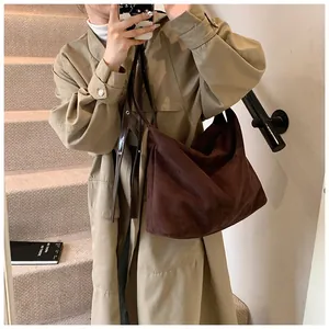 Close-up detail of dark brown suede tote bag with slim leather straps and soft texture