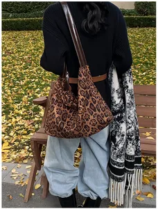 Outdoor shot of a vintage leopard print tote bag with brown leather straps on a park bench