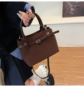 Detail of dark brown matte leather tote bag with silver buckle and thin strap