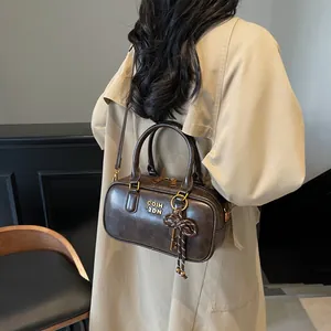 Retro dark brown bowling handbag with metal logo and key charm on khaki trench coat