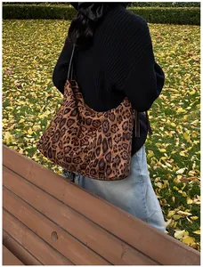 Detail of a large leopard print tote bag carried by a model in an autumn park setting