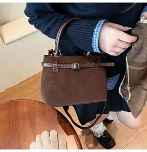 Detail of a brown matte suede tote bag with decorative buckle and smooth leather handle