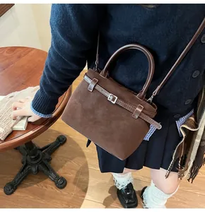 Detailed close-up of a small brown matte leather crossbody bucket bag worn by a model