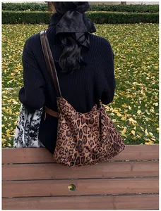 Close-up of leopard print tote bag with leather strap shown in an autumn outdoor setting
