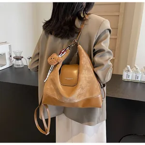 Detail of vintage brown leather tote bag with plush bear charm and ribbon on model