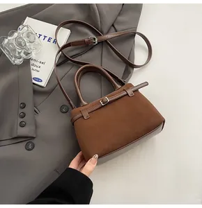 Detail of dark brown matte leather tote bag with metal buckle and smooth stitching