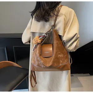 Brown half-moon shoulder bag with vintage texture and cute teddy bear charm on model