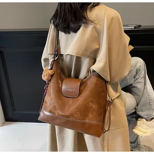 Caramel leather tote bag with plush bear charm worn with a beige trench coat