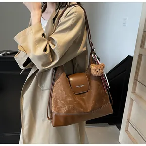 Brown vintage tote bag with plush bear charm worn by model in beige trench coat