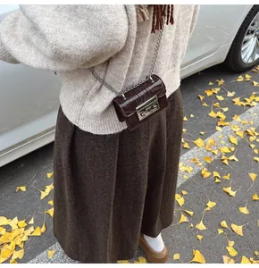 Close-up of mini dark brown patent leather crossbody bag with silver clasp and chain detail