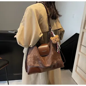 Detail of dark brown tote bag featuring suede textures and a cute bear plush charm