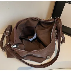 Detailed interior of a brown tote bag featuring a zipper pocket and a fashion label tag