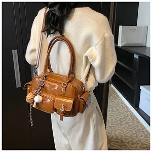 Brown gloss leather shoulder bag shown on model for a retro utilitarian style look