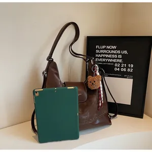 Detailed view of large brown tote bag capacity showing a tablet inside and bear charm
