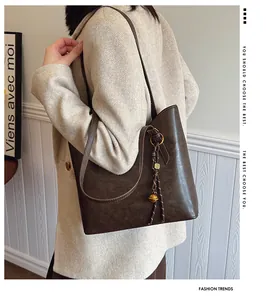 Détail du grand sac cabas marron foncé avec anneau métallique et charme sur modèle