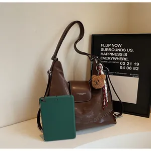 Detail of retro large capacity brown leather tote bag with white stitching and bear charm