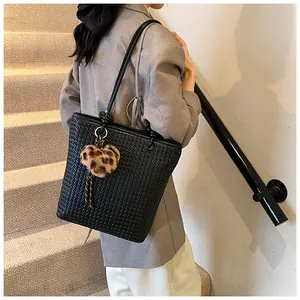 Detail of black woven tote bag with a leopard print heart plush keychain charm
