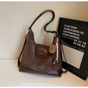 Detail of dark brown tote bag with white contrast stitching and cute plush bear charm