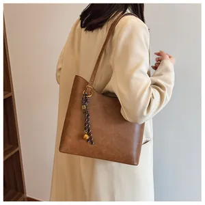 Détail du sac fourre-tout caramel avec pendentif boule dorée et patch triangulaire