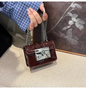 Close-up of a mini dark red leather chain bag with a polished silver clasp on model