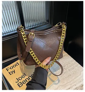 Makro-Detail der dunkelbraunen gesteppten Ledertasche mit elegantem Goldketten-Griff