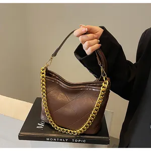 Detail der dunkelbraunen Stepptasche aus Leder mit goldener Kette und Rautenmuster-Struktur