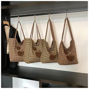 Detailweergave van vier houndstooth tote bags met appelborduursel hangend in een kast