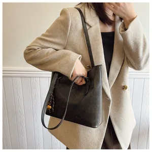 Détail du sac cabas noir avec pendentif tressé et petite cloche dorée élégante