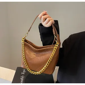Detail der braun gesteppten Hobo-Tasche mit Goldkette und Leder-Schultergurt im Fokus