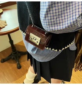 Detail of burgundy patent leather mini square bag with silver lock and chain strap