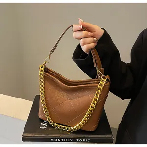 Detailansicht der braunen Stepptasche mit goldener Kette und glatter Ledertextur für Damen