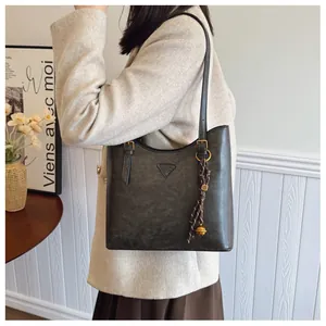 Détail du sac cabas gris foncé avec breloque tressée et texture rétro élégante
