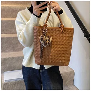 Close-up of brown woven tote bag featuring a leopard print heart plush keychain