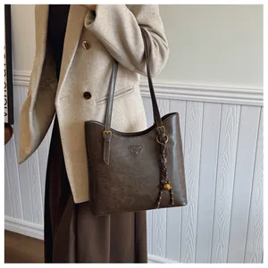 Détail du sac cabas marron foncé avec pendentif cloche dorée et boucle métallique