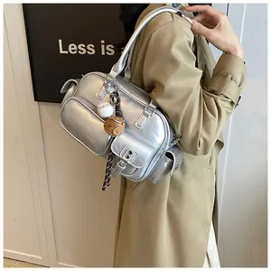 Detail of silver metallic bowling bag with sporty charms on khaki trench coat