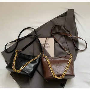 Detail von gesteppten Beuteltaschen in Schwarz und Braun mit goldenen Ketten