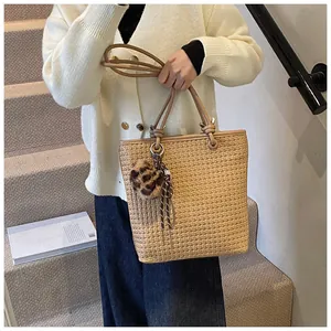 Detailed texture of woven tote bag with leopard plush charm and polka dot ribbon