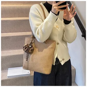 Close-up of woven straw tote bag featuring a decorative leopard print plush ball charm