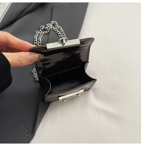 Macro view showing the interior compartment of a mini dark brown patent leather crossbody bag