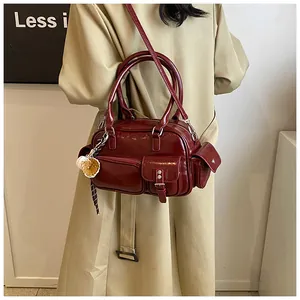Detail view of burgundy leather bowling bag with functional pockets and decorative charms