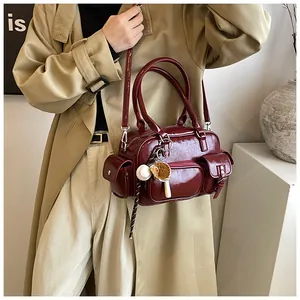 Detail of dark red glossy bowling bag on model with khaki trench coat and baseball charm