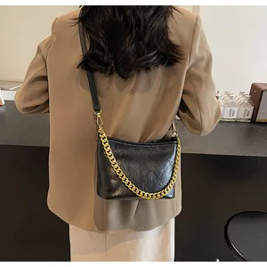 Schwarze gesteppte Hobo-Tasche mit goldener Kette am Modell in Nahaufnahme