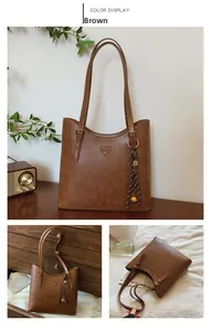 Détail d'un cabas en cuir marron avec logo triangle et pendentif pompon clochette tressé